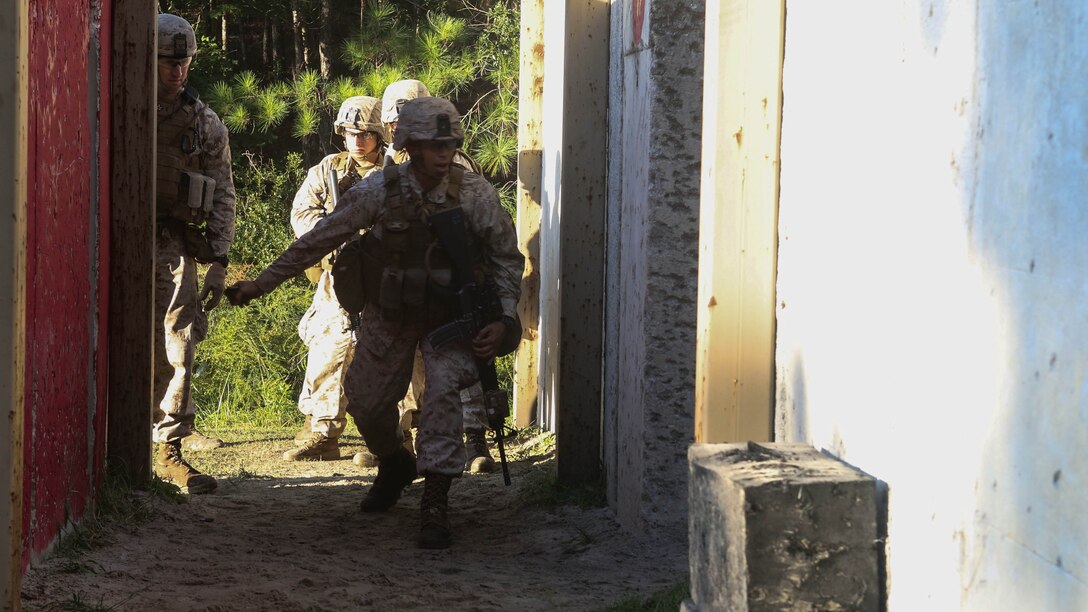 A Marine with 2nd Battalion, 6th Marine Regiment, 2nd Marine Division, II Marine Expeditionary Force throws a grenade into a building during a training exercise at MOC-3 range aboard Marine Corps Base Camp Lejeune, N.C., Oct. 21, 2014. The Marines spent hours preparing for their live-fire event, honing their teams to communicate from the point of entry into the building and on through rooms filled with enemy targets.