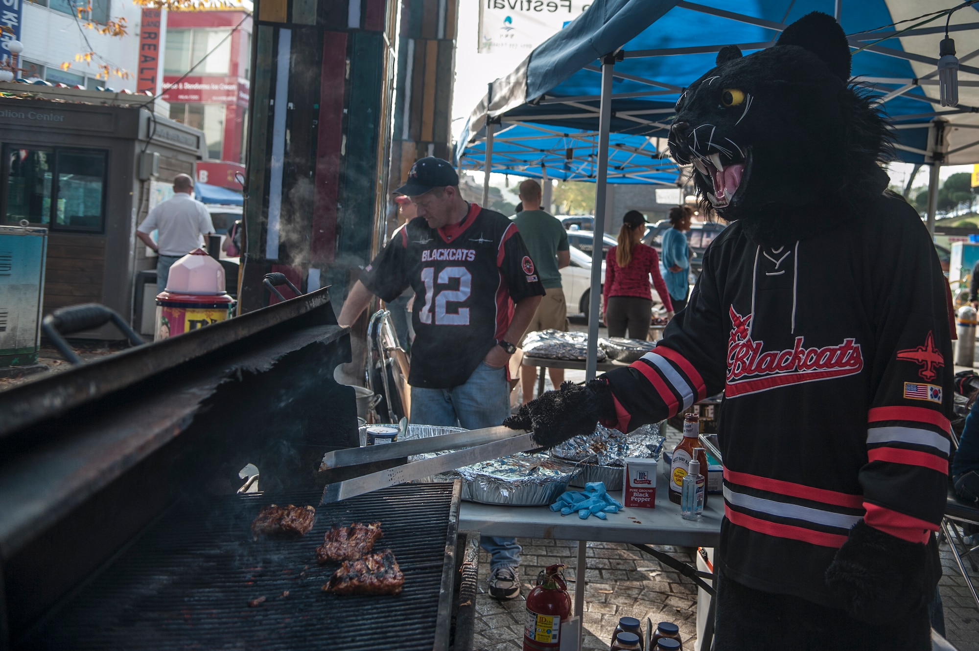 Oscar the Blackcat, 5th Reconnaissance Squadron mascot, grills chicken during the 11th Korean American Friendship Cultural Festival at the Songtan Entertainment District, Republic of Korea, Oct. 25, 2014. Multiple Squadrons from Osan Air Base hosted booths during the two-day event. (U.S. Air Force photo by Senior Airman Matthew Lancaster)