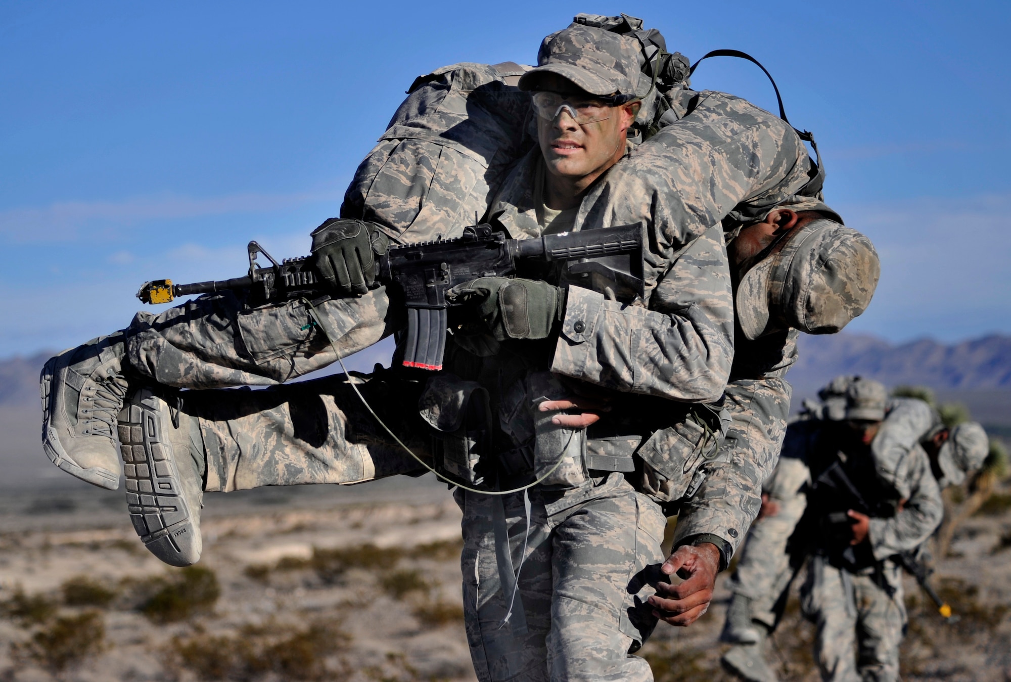 Senior Airman Zachary Baldridge, 20th Security Forces Squadron member, Shaw Air Force Base, South Carolina, carries a simulated casualty back to the rest of the squad during a foot patrol during the Ranger Assessment Course Oct. 8, 2014, at Silver Flag Alpha range, Nevada. Students are ambushed by simulated enemies and must use small unit tactics and work as team to neutralize the threat. (U.S. Air Force photo by Airman 1st Class Christian Clausen/Released)