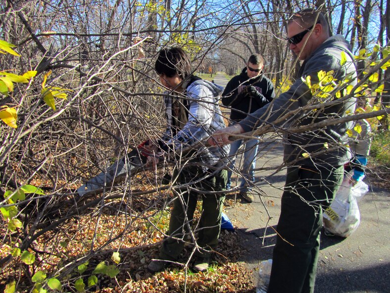 Master Sgt. Chris Miller, Grand Forks Air Force Base Boy Scout Troop 319 leader, holds a branch steady while Tenderfoot William Swaim cuts it off during a community service project on Grand Forks Air Force Base, Oct. 25, 2014. The members of Troop 319 hiked the length of the 5K trail clearing brush and removing litter and debris. (Courtesy photo)