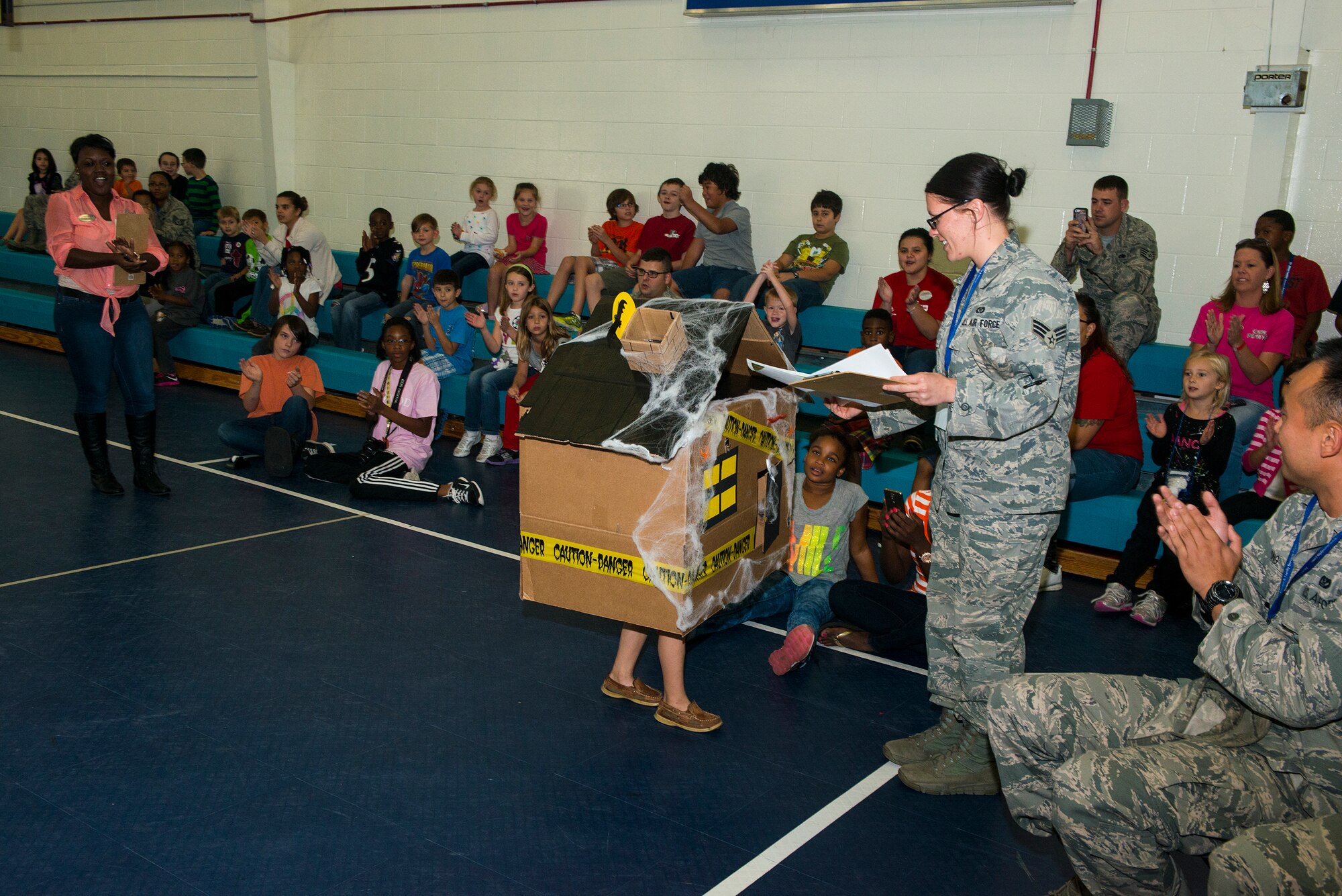 U.S. Air Force Senior Airman Paige Vanpelt, 23d Civil Engineer Squadron, awards a certificate to Ryan, son of Staff Sgt. Travis Baldwin, during the Energy Action Month Costume Contest Oct. 24, 2014, at Moody Air Force Base, Ga. The 23d CES created the contest to show youth creative ways to conserve resources, while still having fun. (U.S. Air Force photo by Airman 1st Class Ceaira Tinsley/Released)