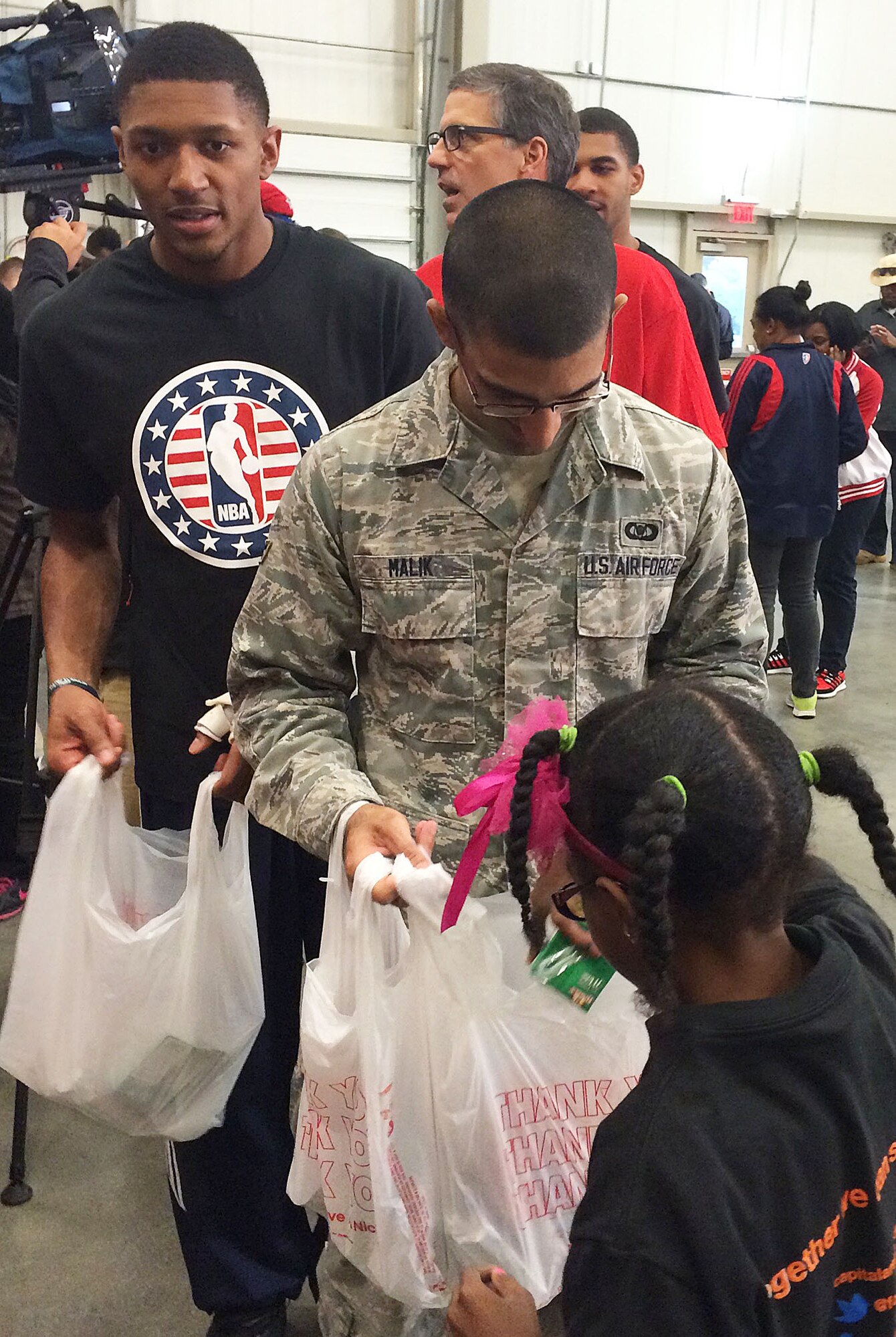 Airman 1st Class Zane Malik, 11th Wing Command Post, and Washington Wizards’ Guard Bradley Beal wait in line for a volunteer from Browne Education Campus to fill bags with food for the Capital Area Food Bank’s Weekend Bag Program at the Capital Area Food Bank in Washington, D.C., Oct 24, 2014. According to a study by the Capital Area Food Bank and Feeding America, hunger in the Washington metro area increased by 11 percent in the last four years. (U.S. Air Force photo/Mike Martin)