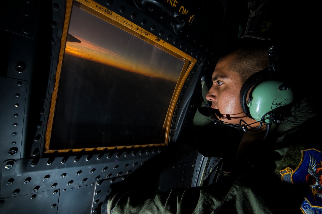 U.S. Air Force Senior Airman Edgar Perez, 71st Rescue Squadron loadmaster, watches the sun set from the window of an HC-130P Combat King Aug. 28, 2014, in the skies over Georgia. The 71st RQS took part in the search and rescue efforts for a downed Air National Guard F-15C Eagle pilot who went missing after a crash on Aug. 27. (U.S. Air Force photo by Airman 1st Class Ryan Callaghan/Released)