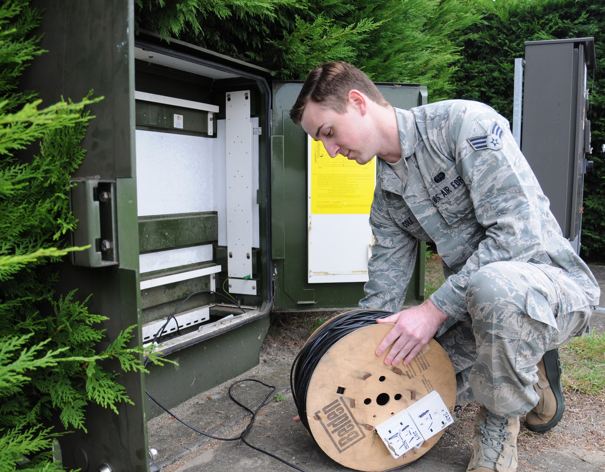 U.S. Air Force Senior Airman Christopher Cole, 100th Communication Squadron cyber transport technician from Merced, Calif., reels out cable at a distribution point on the flightline to help an aircraft communicate with the base Sept. 17, 2014, on RAF Mildenhall, England. Cole’s efforts enable aircraft to connect to the global information grid. Planes connect to analog lines as they don’t have wireless communication capabilities to connect to the defence switched network telephones. (U.S. Air Force photo by Gina Randall/Released) 