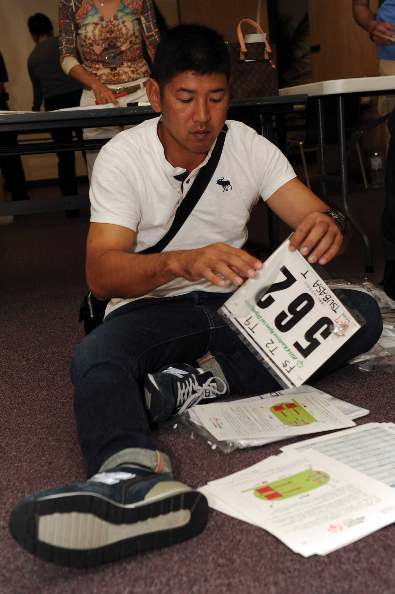 Iha Mitsutada, 18th Munitions Squadron ammunition foreman, pairs sports bibs with maps showing the location of athletic events in preparation for Kadena Special Olympics on Kadena Air Base, Japan, Oct. 23, 2014. More than 100 volunteers gathered at the Schilling Community Center to prepare packages for KSO athletes, each of which included a sports bib displaying the athlete?s name, participant number and events in which they?ll participate, a T-shirt and a map showing the location of each event. (U.S. Air Force photo by Airman 1st Class Zade C. Vadnais/Released)