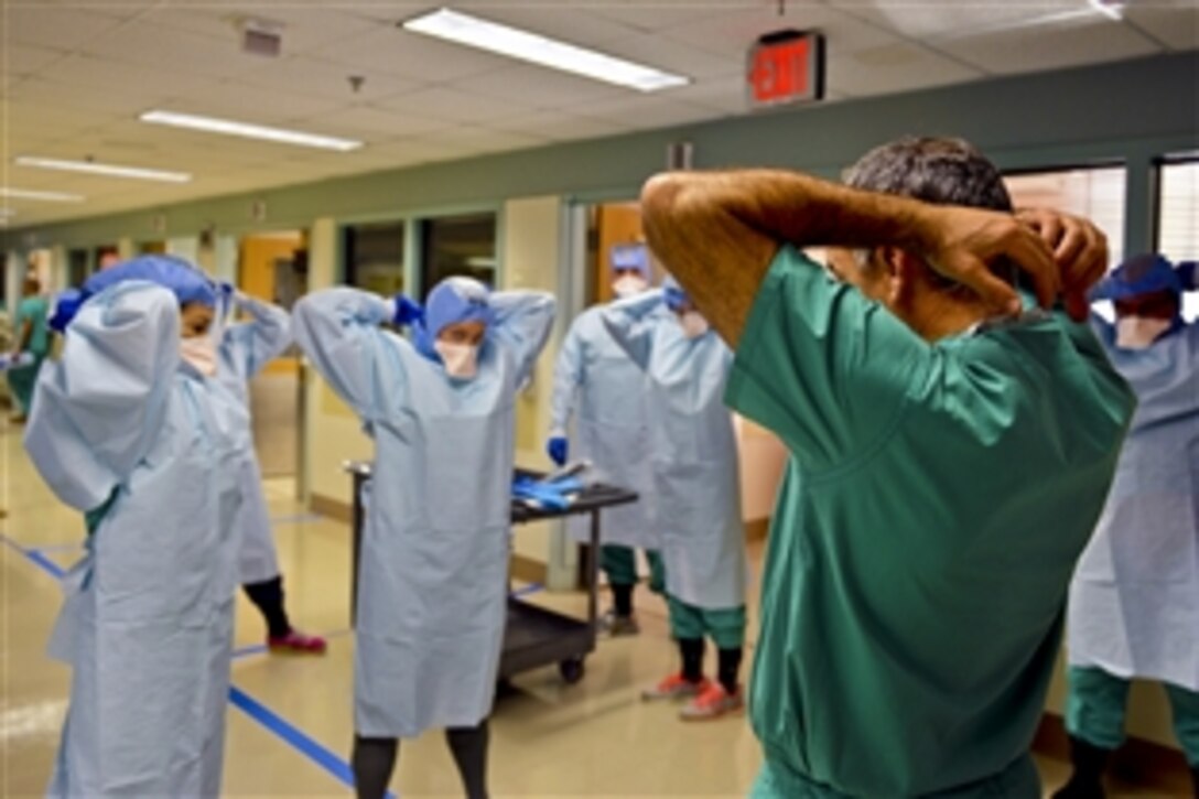 Navy Cmdr. James Lawler, right, a member of the Defense Department medical support team, shows students how to remove their personal protective equipment during training at the San Antonio Military Medical Center in San Antonio, Oct. 24, 2014. The students are part of a 30-person team prepared to deploy in the event of an Ebola crisis in the United States. 