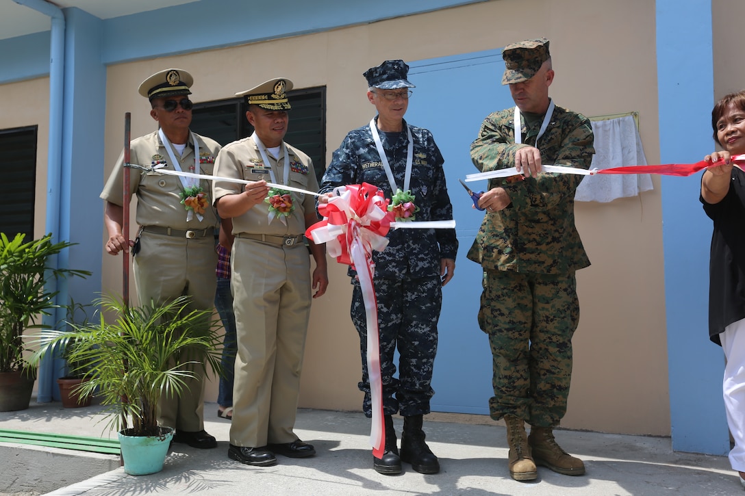 Philippine Navy, Rear Admiral Jose Renan Suarez, commander of Naval Education and Training Command, U.S. Navy Rear Admiral Hugh D. Wetherald, commander of Amphibious Force Seventh Fleet, and U.S. Marine Corps Brig. Gen. Paul Kennedy, commanding general, 3d Marine Expeditionary Brigade, cut a ribbon at the closing ceremony for a renovated classroom during Amphibious Landing Exercise (PHIBLEX) 15 at Beddeng-Mabangcal Elementary, Zambales, Philippines, Oct. 9, 2014. PHIBLEX is an annual, bilateral training exercise conducted by the Armed Forces of the Philippines, U.S. Marines and Navy to strengthen interoperability across a range of capabilities to include disaster relief and contingency operations. (U.S. Marine Corps photo by MCIPAC Lance Cpl. Colby Cooper/Released)