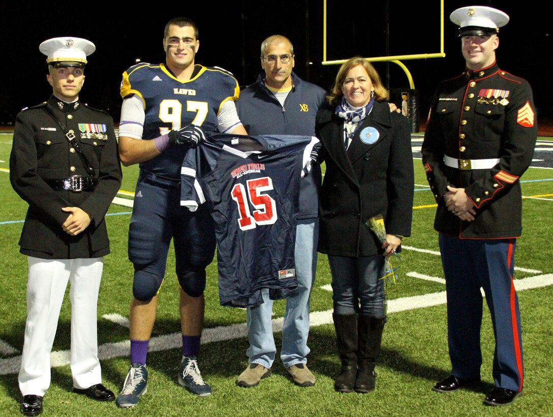 Joe Gaziano is presented with his jersey for the Semper Fidelis All-American Bowl game Oct. 24. The presentation took place, as a part of senior night ceremonies at Xaverian Brothers High School. Joe is accompanied by his parents, Mary Ellen and Frank Gaziano, as well as, Capt. Zachary Johnson, Recruiting Station Portsmouth's executive officer and Sgt. Keily Warren, the school's canvassing recruiter. Joe Gaziano will be attending Northwestern University next year on a football scholarship. The Semper Fidelis All-American game will be broadcasted live on Fox Sports 1 from the StubHub Center in Carson, California Jan.4, 2015 at 9 pm EST. Joe is a native of Scituate, Massachusetts and both of his grandfathers served in the Marine Corps during World War II. 