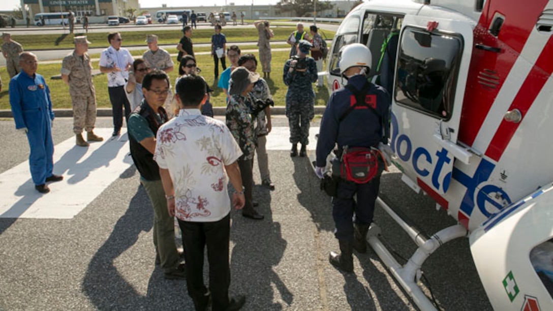 Tetsuji Matsumoto, foreground, speaks to Okinawan residents who live near Camp Kinser and civilian air ambulance staff, as Maj. Gen. Charles L. Hudson, left background and Alfred Magleby, left background and other visitors at Exercise Constant Vigilance 2014 view the civilian air ambulance known as “Doctor Heli” here, Oct. 28. Emergency responders from Urasoe City transported a simulated casualty in the air ambulance to Camp Kinser, rehearsing a scenario in which the civilian landing zone was blocked due to a natural disaster. The exercise, which included personnel assigned to the Japan Self-Defense Force, Marine Corps Installations Pacific-Marine Corps Base, Camp Butler Japan, Urasoe City, Camp Kinser emergency services, Department of Defense Dependents Schools, and other civilian agencies, simulated a collaborative emergency response to a tsunami and tested cooperative emergency response procedures. Matsumoto is the mayor of Urasoe City. Magleby is the U.S Consul General, Naha. Hudson is the commanding general of MCIPAC-Marine Corp Base, Camp Butler Japan. (U.S. Marine Corps photo by Sgt. Matthew Manning/Released)