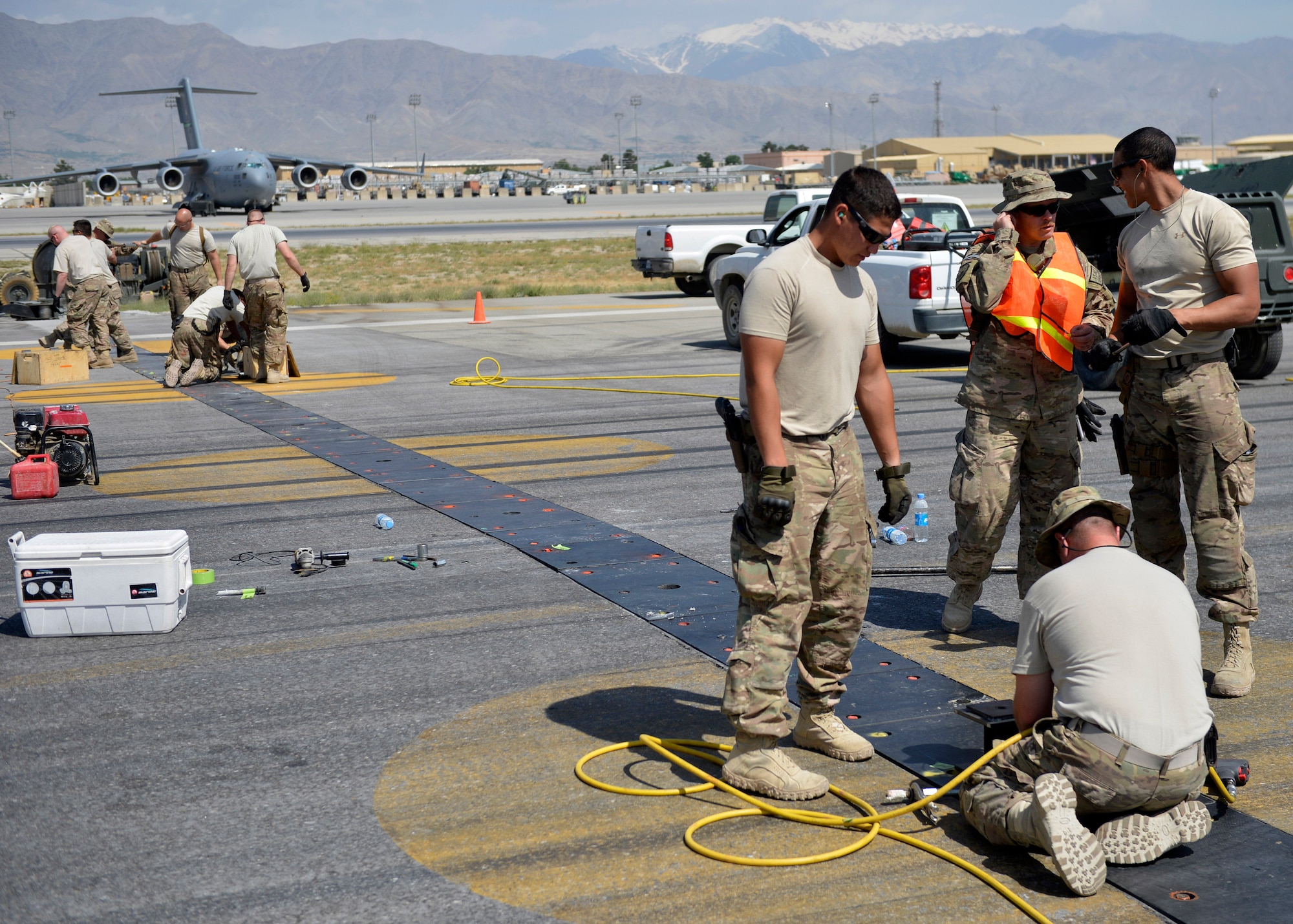 U.S. Air Force Airmen with the 455th Expeditionary Civil Engineer Squadron, grind down bolts on a polly pad on the flightline at Bagram Airfield, Afghanistan June 5, 2014. Grinding down the bolts is necessary to prevent aircraft from popping tires when running over the polly pad. (U.S. Air Force photo by Staff Sgt. Evelyn Chavez/Released)