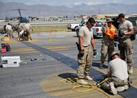 U.S. Air Force Airmen with the 455th Expeditionary Civil Engineer Squadron, grind down bolts on a polly pad on the flightline at Bagram Airfield, Afghanistan June 5, 2014. Grinding down the bolts is necessary to prevent aircraft from popping tires when running over the polly pad. (U.S. Air Force photo by Staff Sgt. Evelyn Chavez/Released)