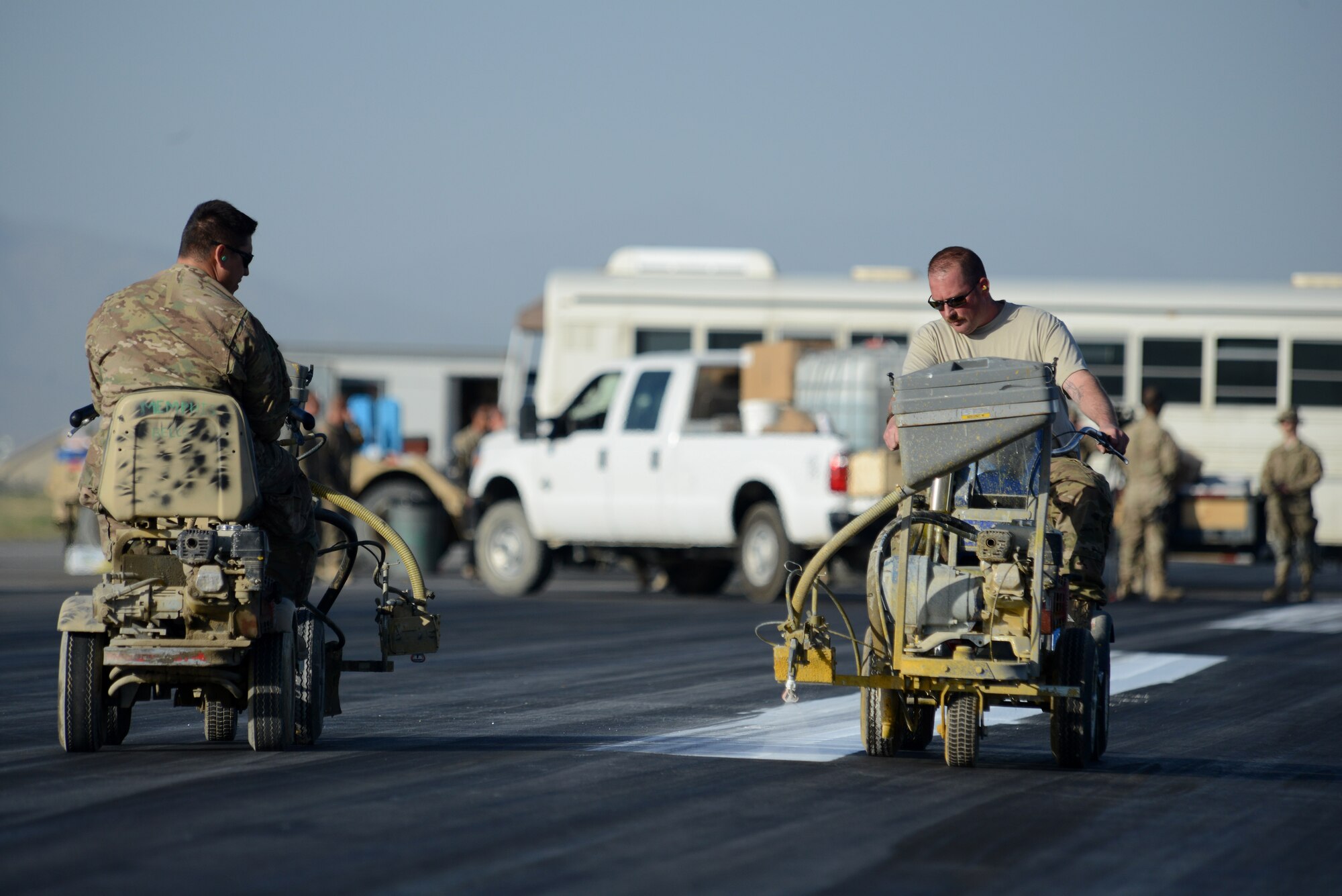 U.S. Air Force Airmen with the 455th Expeditionary Civil Engineer Squadron, paint the flightline at Bagram Airfield, Afghanistan June 8, 2014. The 455 ECES ensures operability of the airfield by providing airfield maintenance, construction and operation for the senior airfield authority mission. (U.S. Air Force photo by Master Sgt. Cohen A. Young/Released)
