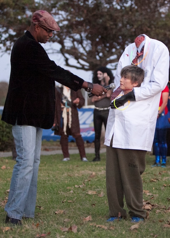 Gunnery Sgt. Terence Harrell asks 9-year-old Ethan Baldwin what his costume is during the Marine Aircraft Group 36 costume contest Oct. 18 here. MAG-36 hosted the costume contest to raise money for the 239th Marine Corps Ball. Baldwin took first place as a headless scientist in the 13-and-under category of the costume contest. Harrell is the communications chief with MAG-36, 1st Marine Aircraft Wing, III Marine Expeditionary Force. Baldwin is the son of Lt. Col. Matthew Baldwin the S-1, administration officer with MAG-36, 1st MAW, III MEF.