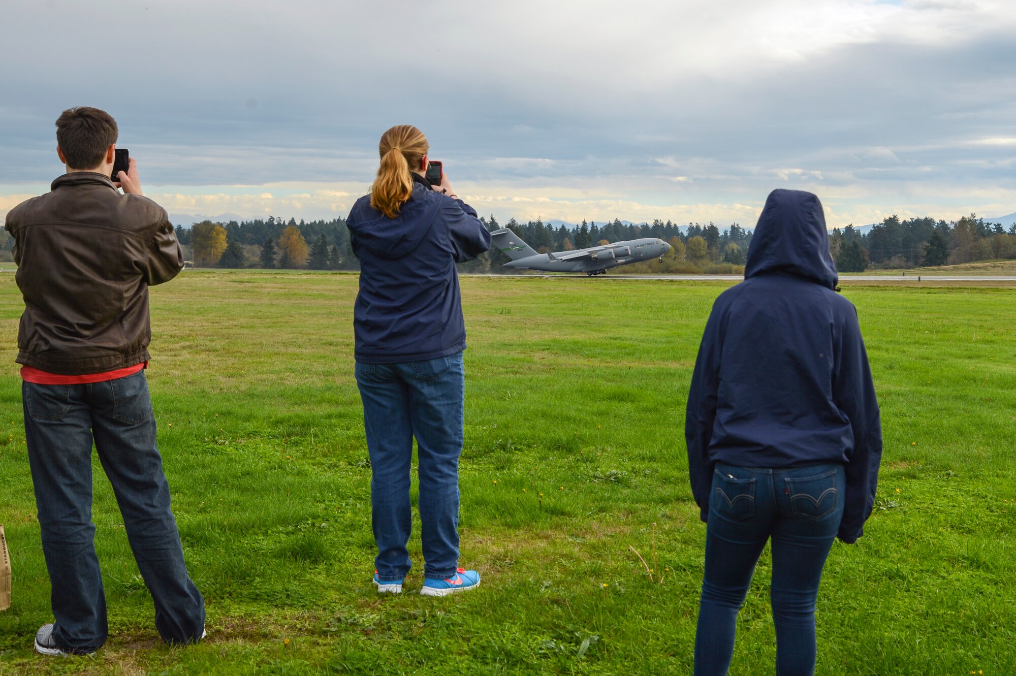 Students from the Aviation Explorer Post 1735 take photos of a C-17 Globemaster III taking off October 25, 2014, during their tour of Joint Base Lewis-McChord, Wash. During their time at McChord Field, they visited the aircrew flight equipement shop, the air control tower, the C-17 simulator complex and the field training detachment. (U.S. Air Force photo/Airman 1st Class Keoni Chavarria)