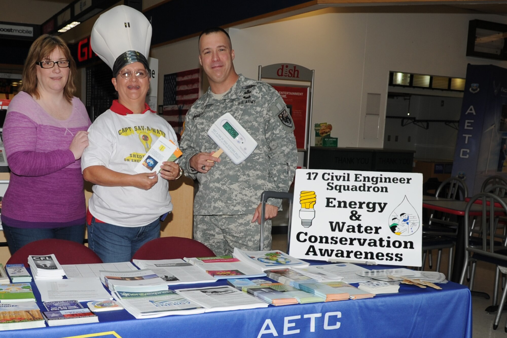GOODFELLOW AIR FORCE BASE, Texas -- Mary C. Lumsdon, 17th Civil Engineer Squadron base energy manager, poses with Army Command Sgt. Maj. Naamon J. Grimmett, 344th Military Intelligence Battalion, and A. Marie Grimmett, Exchange customer, at an Energy Awareness booth in the Exchange Concession Area Oct. 17. The booth provided flyers on energy awareness and ways to save energy and money. (U.S. Air Force photo/ Staff Sgt. Laura R. McFarlane)
