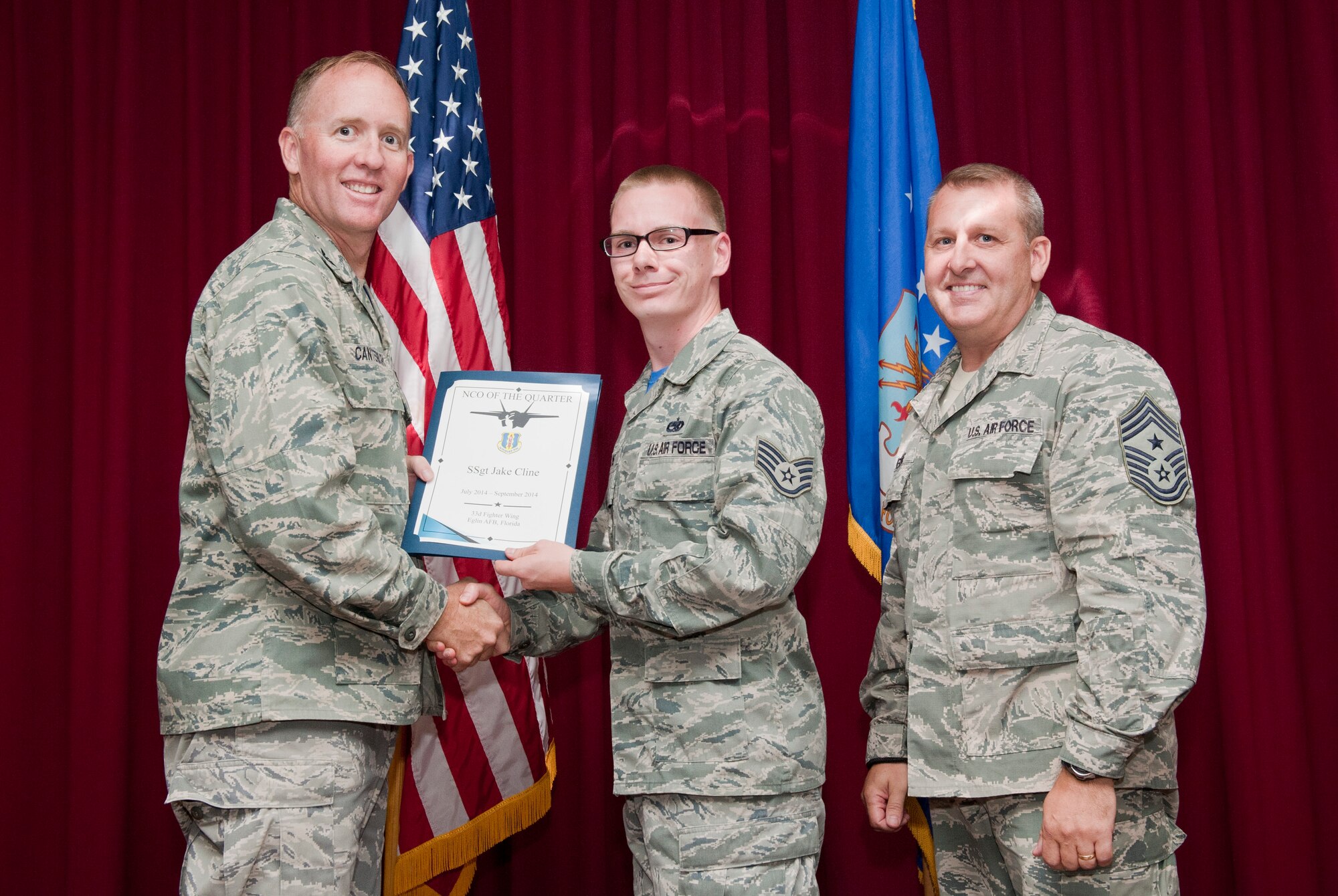 Staff Sgt. Jake Cline, 33rd Maintenance Group crew chief, is presented the 33rd Fighter Wing non-commissioned officer of the quarter award from Col. Todd Canterbury, 33rd FW commander, and Chief Master Sgt. Scott Berge, 33rd FW command chief, on Eglin Air Force Base, Fla., Oct 17, 2014. Cline led an Autonomic Logistics Information System working group designed to draft the first technical manual aimed at filling the gap between Air Force Instructions and Lockheed Martin sustainment operating instructions. (U.S. Air Force photo/Staff Sgt. Marleah Robertson)