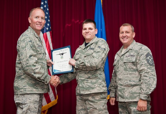 Airman 1st Class Daniel Phelan, 33rd Maintenance Group metals technician, is presented the 33rd Fighter Wing innovator of the month award for August from Col. Todd Canterbury, 33rd FW commander, and Chief Master Sgt. Scott Berge, 33rd FW command chief, on Eglin Air Force Base, Fla., Oct 17, 2014. Phelan designed a nutplate push-test adapter and built an engine trailer platform which eliminated possible foreign object debris and wrote a computer numerically-controlled program. (U.S. Air Force photo/Staff Sgt. Marleah Robertson)