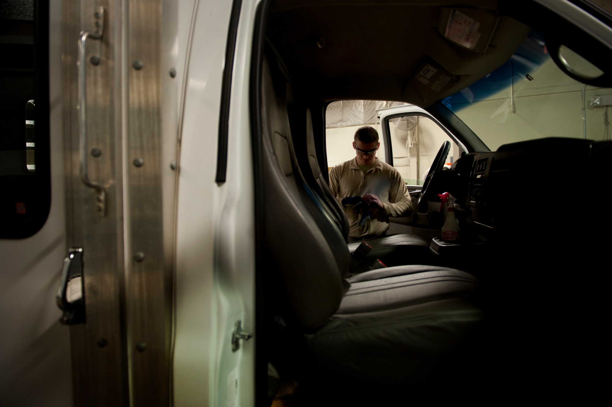Staff Sgt. Keegan Chaptintovey, 5th Logistics Readiness Squadron allied trades NCO in charge, puts on gloves before removing the window shield from a vehicle on Minot Air Force Base, N.D., Oct. 17, 2014. Vehicle mechanics are responsible for the maintenance of all government-owned vehicles on base.  (U.S. Air Force photo/Senior Airman Brittany Y. Bateman)