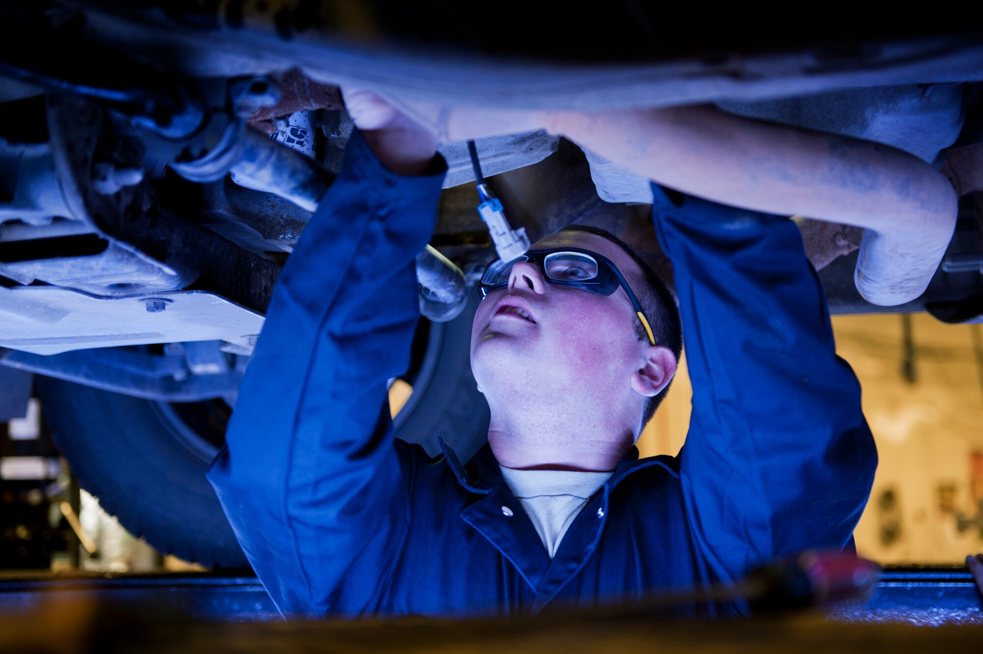 Airman 1st Class Steven Schott, 5th Logistics Readiness Squadron vehicle maintenance apprentice, changes the oxygen sensors under a vehicle on Minot Air Force Base, N.D., Oct. 17, 2014. Airmen from the 5th LRS vehicle maintenance flight repair and maintain various types of vehicles to ensure Minot AFB stays mobile. (U.S. Air Force photo/Senior Airman Brittany Y. Bateman)