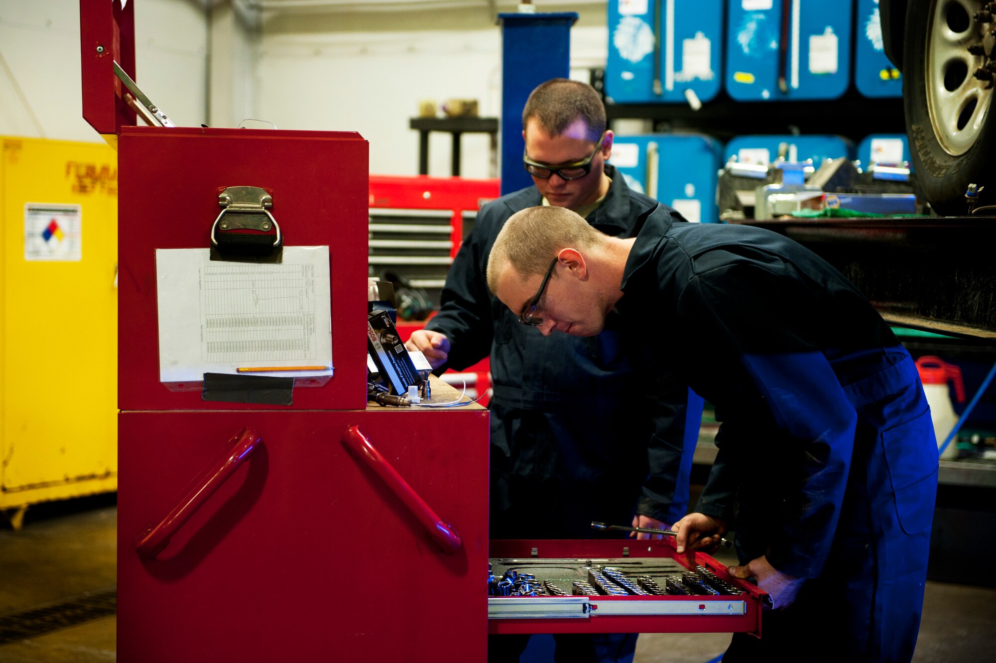 Airmen 1st Class Steven Schott and Gray Bishop, 5th Logistics Readiness Squadron vehicle maintenance apprentices, look in their tool box before performing maintenance on a vehicle on Minot Air Force Base, N.D., Oct. 17, 2014. Vehicle mechanics are responsible for the maintenance of all government-owned vehicles on base. (U.S. Air Force photo/Senior Airman Brittany Y. Bateman)