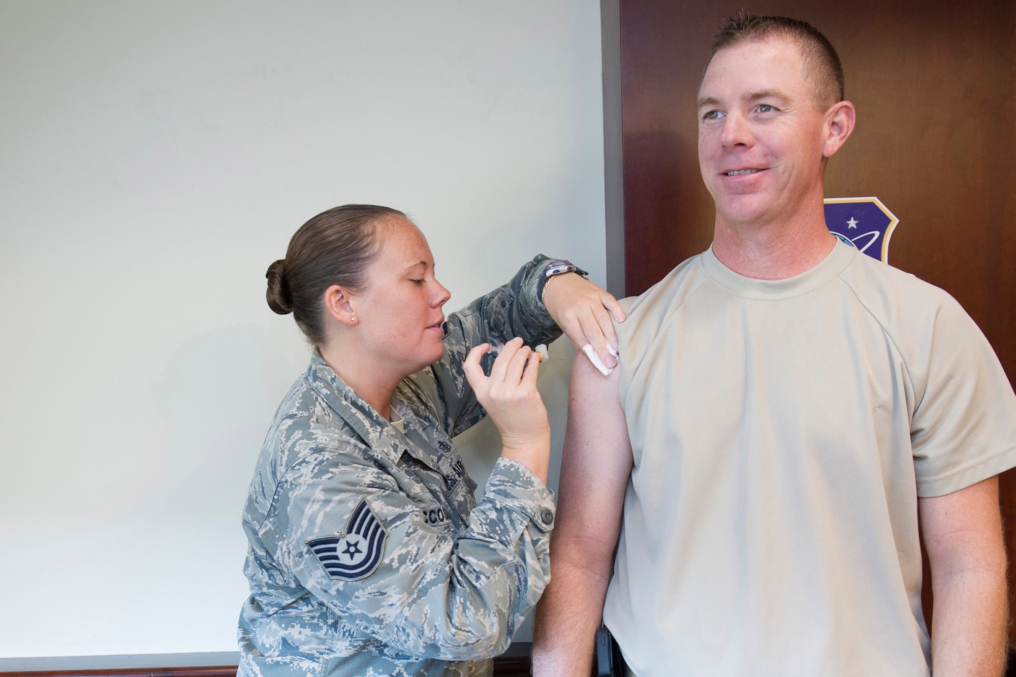 Tech. Sgt. Sara McCoskey, 45th Aerospace Medical Squadron independent duty medical technician, administers an influenza vaccine to Chief Master Sgt. Craig Neri, 45th Space Wing command chief, Oct. 27, 2014, at Patrick Air Force Base, Fla. The influenza vaccine is now available at the 45th Medical Group Allergy and Immunization Clinic. (U.S. Air Force photo/Matthew Jurgens/Released) 