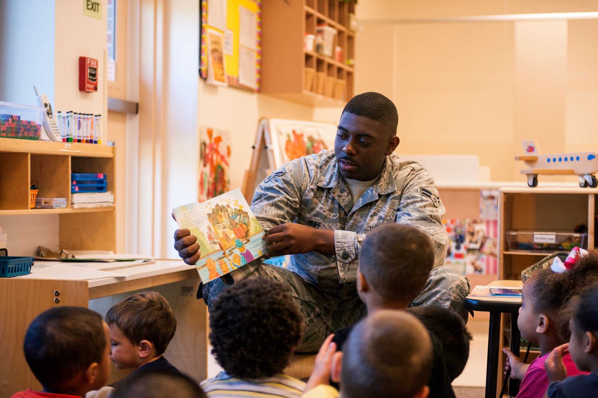 U.S. Air Force Airman 1st Class Elton Huff, 23d Civil Engineer Squadron engineering journeyman, reads a recycling story to children at the Child Development Center II Oct. 28, 2014, at Moody Air Force Base, Ga. Throughout the month, the CES provided tips for energy conservation and hosted a recycled materials costume contest at the youth center. (U.S. Air Force photo by Senior Airman Olivia Bumpers/Released) 