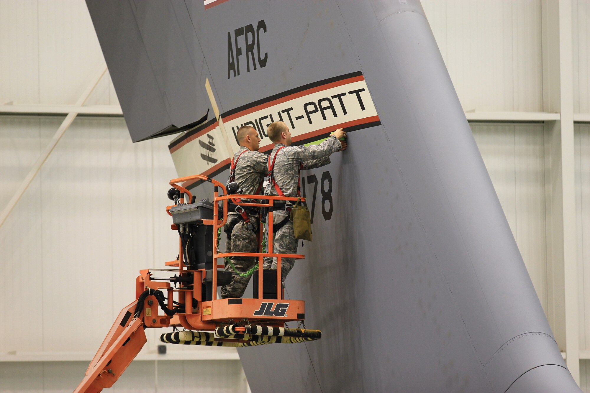 WRIGHT-PATTERSON AIR FORCE BASE, Ohio - Staff Sgt. George Goff and Senior Airman Matthew Gideon, 445th Maintenance Squadron, aircraft structural maintenance, apply a new tailband over a newly acquired C-17 Globemaster III Oct. 5, 2014. The aircraft was transferred from Altus Air Force Base, Oklahoma and has an extended range fuel tank, allowing the aircraft to fly further without refueling. (U.S. Air Force photo/Tech. Sgt. Patrick O'Reilly)