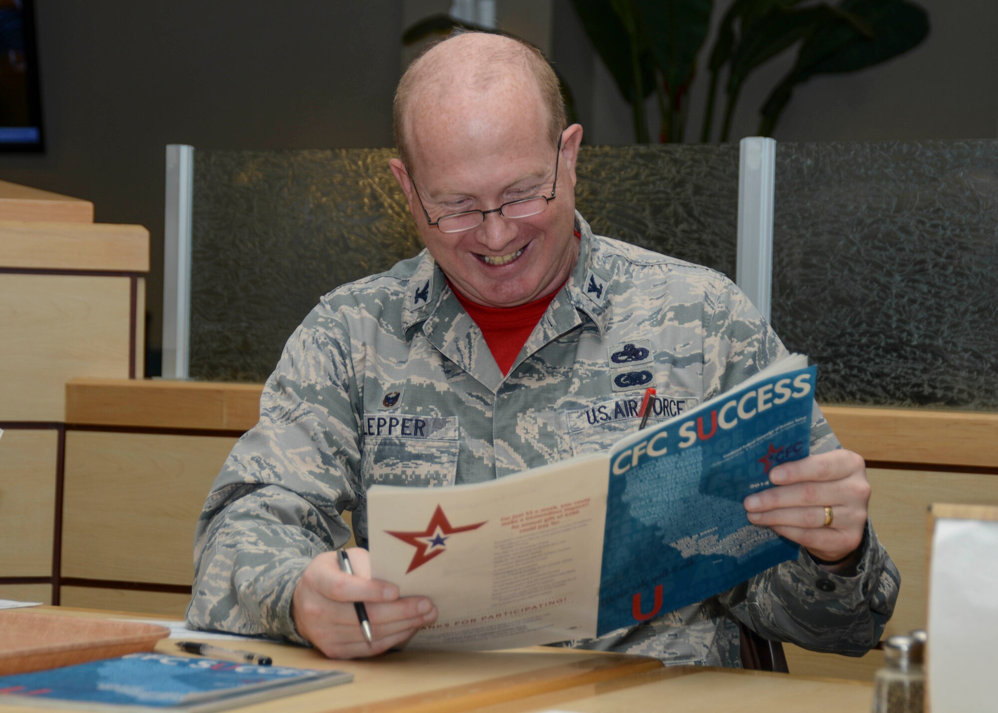 Col. Robert Lepper, Jr., 412th Maintenance Group commander, reads through the catalog of charities, all registered with the IRS. The Combined Federal Campaign kick-off breakfast on Oct. 24 marked the start of a six-week fundraising campaign. (U.S. Air Force photo by Rebecca Amber)