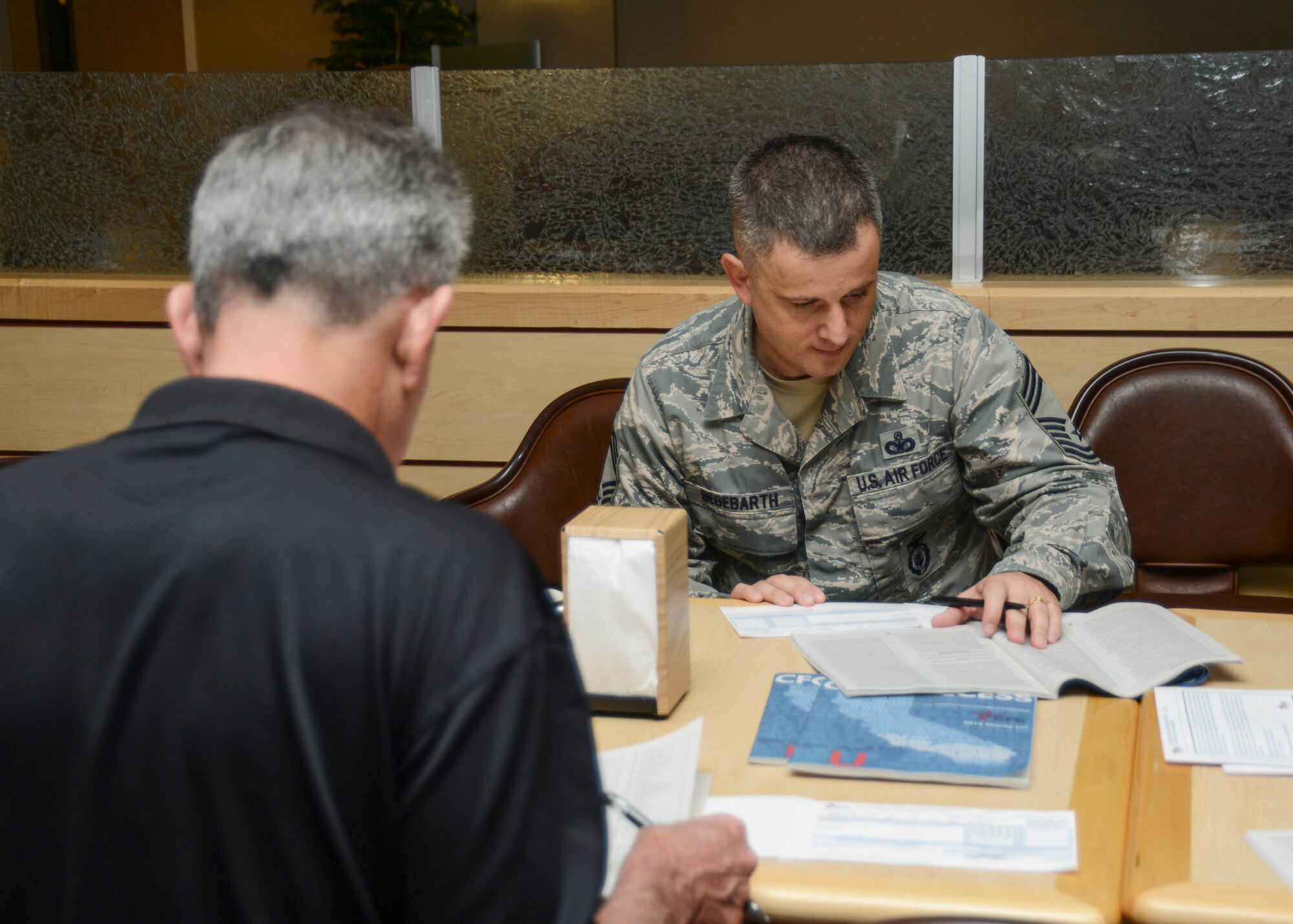 Chief Master Sgt. James Segebarth, 412th Security Forces Squadron superintendent, looks through the list of 22,000 charities that the Combined Federal Campaign supports. The catalog is organized by genre and answers commonly asked questions, like the charity’s overhead costs. (U.S. Air Force photo by Rebecca Amber)