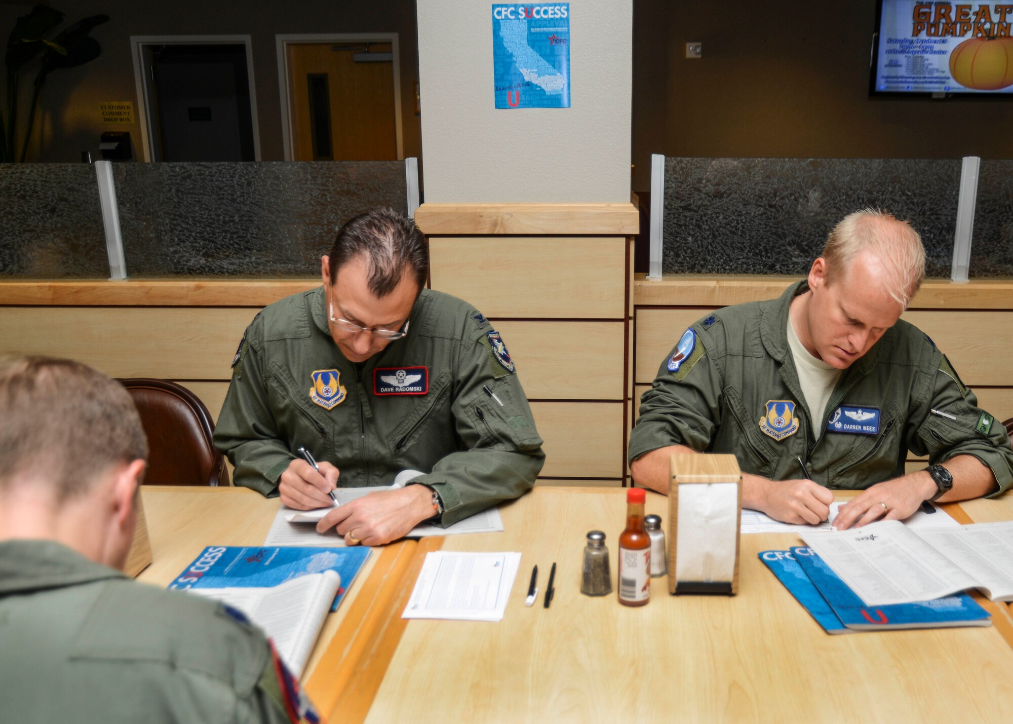Col. David Radomski, 412th Test Wing vice commander, and Lt. Col. Darren Wees, 445th Flight Test Squadron commander, fill out their pledge forms at the Edwards Combined Federal Campaign kick-off breakfast in the Joshua Tree Dining Facility Oct. 24. (U.S. Air Force photo by Rebecca Amber) 
