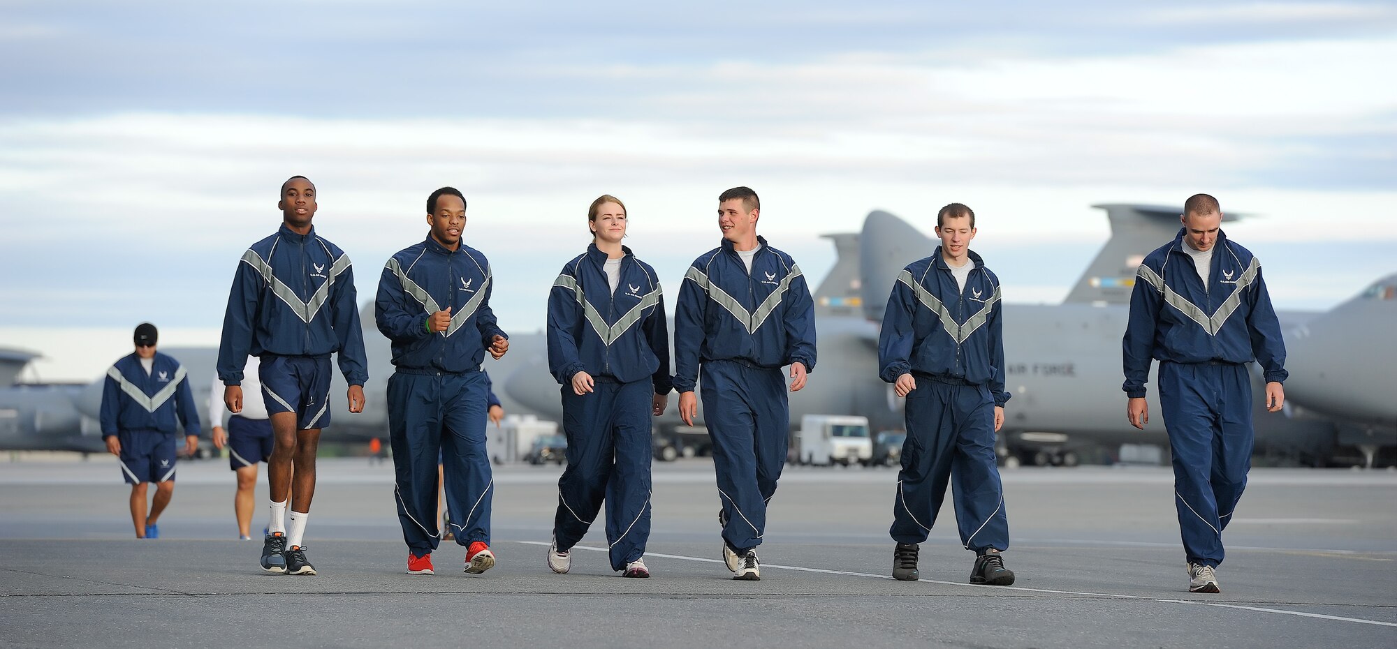 A group of Airmen from the 436th Airlift Wing walk along the flight line with C-5M Super Galaxy aircraft visible in the background during the 2014 Wingman Day 5K Fun Run on Oct. 24, 2014, at Dover Air Force Base, Del. Chilly temperatures greeted the participants for the morning run.  (U.S. Air Force photo/Greg L. Davis)