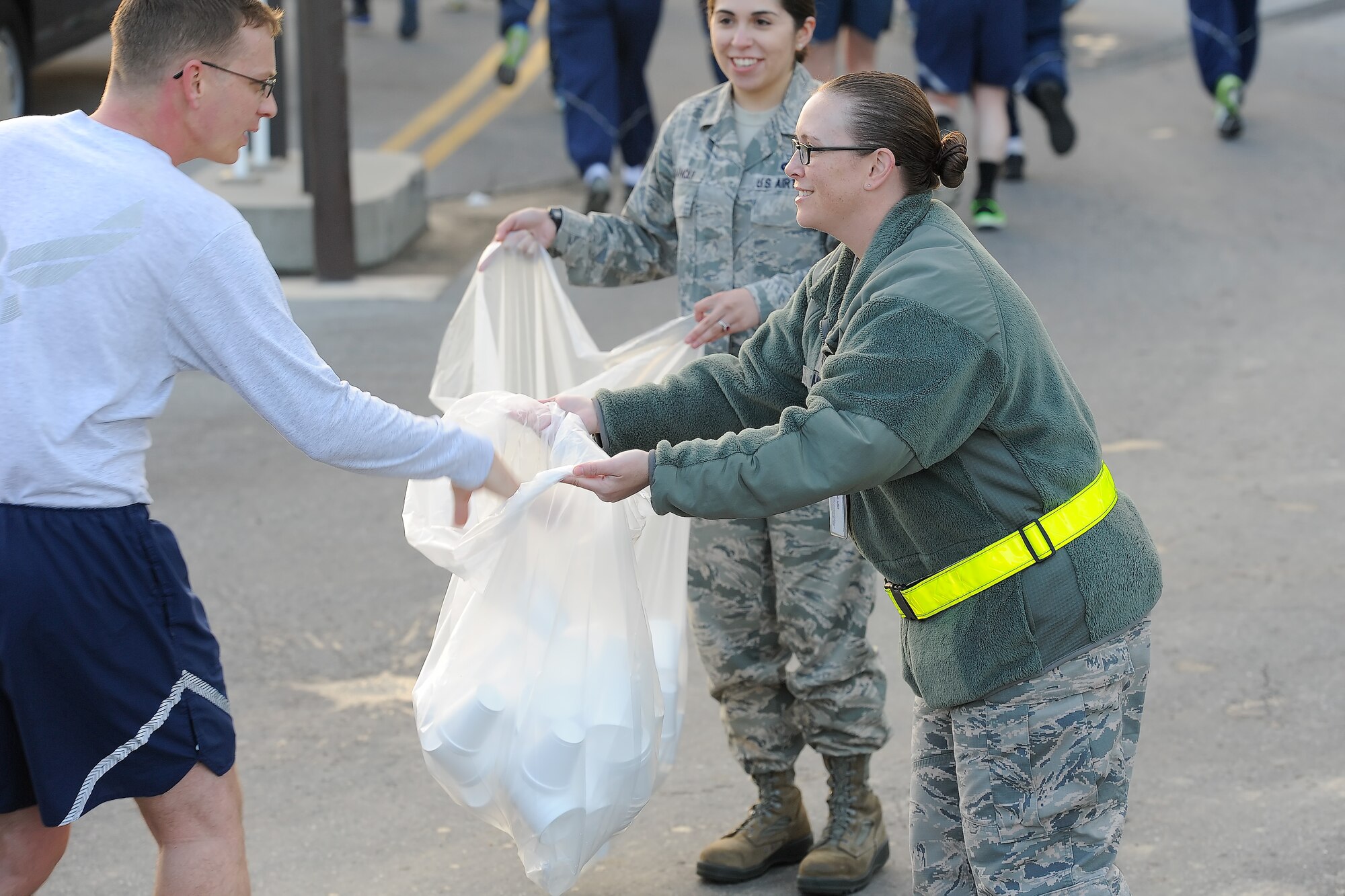 Master Sgt. Brea Misho, 436th Operations Support Squadron, holds out a trash-bag to accept used water cups from runners participating in the 2014 Wingman Day 5K Fun Run on Oct. 24, 2014, at Dover Air Force Base, Del. Misho and others ensured trash was collected in bags to prevent it from being blown onto the flight line and creating a hazard. (U.S. Air Force photo/Greg L. Davis)