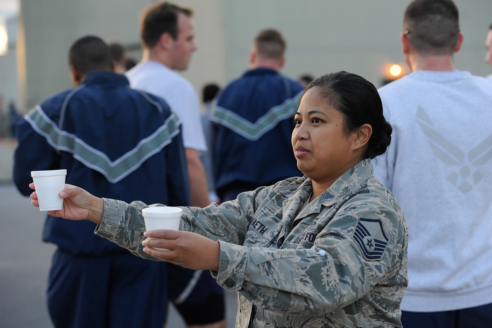Master Sgt. Yasmin Vaeth, 436th Contracting Squadron, hands out cups of water to runners at a refreshment station along the course of the 2014 Wingman Day 5K Fun Run on Oct. 24, 2014, at Dover Air Force Base, Del. Vaeth and others handed out water to ensure runners stayed hydrated during the run. (U.S. Air Force photo/Greg L. Davis)