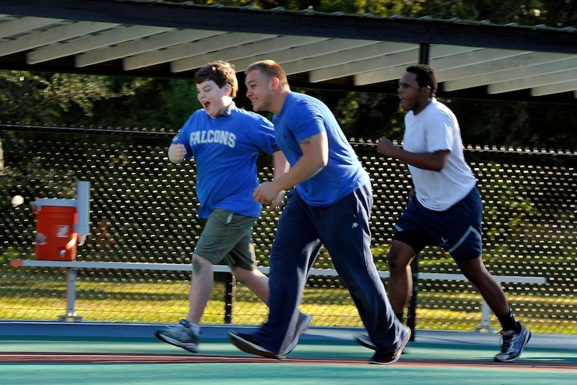 Falcons team member Ashton (left) runs for home plate with his buddies, Senior Airman Charles Cannon and Airman 1st Class Khalil Edmondson, 437th Maintenance Squadron, during a Miracle League baseball game versus the Green Wave Oct. 25, 2014, in Summerville, S.C. The Miracle League assists special needs children who play baseball with the assistance of volunteer buddies. Each week of the season, a different squadron from the 437th Airlift Wing volunteers to be "buddies" and assist the children playing ball. (U.S. Air Force photo/Staff Sgt. Renae Pittman)