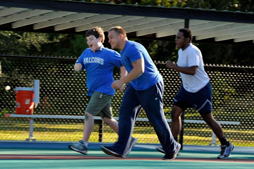 Falcons team member Ashton (left) runs for home plate with his buddies, Senior Airman Charles Cannon and Airman 1st Class Khalil Edmondson, 437th Maintenance Squadron, during a Miracle League baseball game versus the Green Wave Oct. 25, 2014, in Summerville, S.C. The Miracle League assists special needs children who play baseball with the assistance of volunteer buddies. Each week of the season, a different squadron from the 437th Airlift Wing volunteers to be "buddies" and assist the children playing ball. (U.S. Air Force photo/Staff Sgt. Renae Pittman)