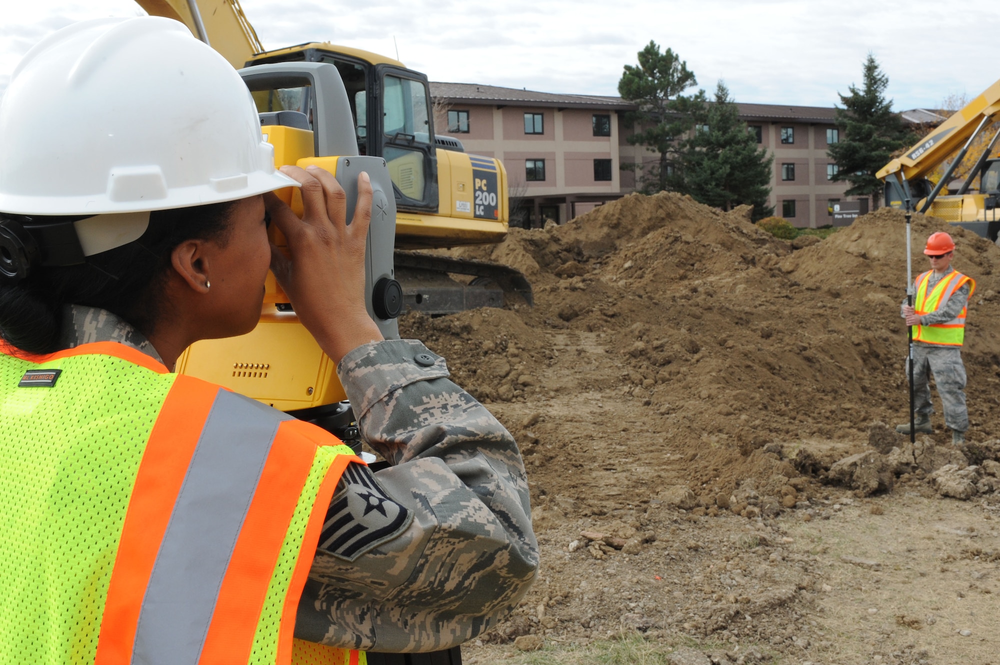 Staff Sgt. Lawanda Perthel, 28th Civil Engineer Squadron project instructor, uses a total station and prism apparatus to survey a construction site with Staff Sgt. Reuben Gingerich, 28th CES engineer technician, at Ellsworth Air Force Base, S.D., Oct. 23, 2014. The equipment sends out a radar signal, bounces off the prism and provides engineers with the distance and angle of the site. (U.S. Air Force photo by Senior Airman Hailey R. Staker/Released)