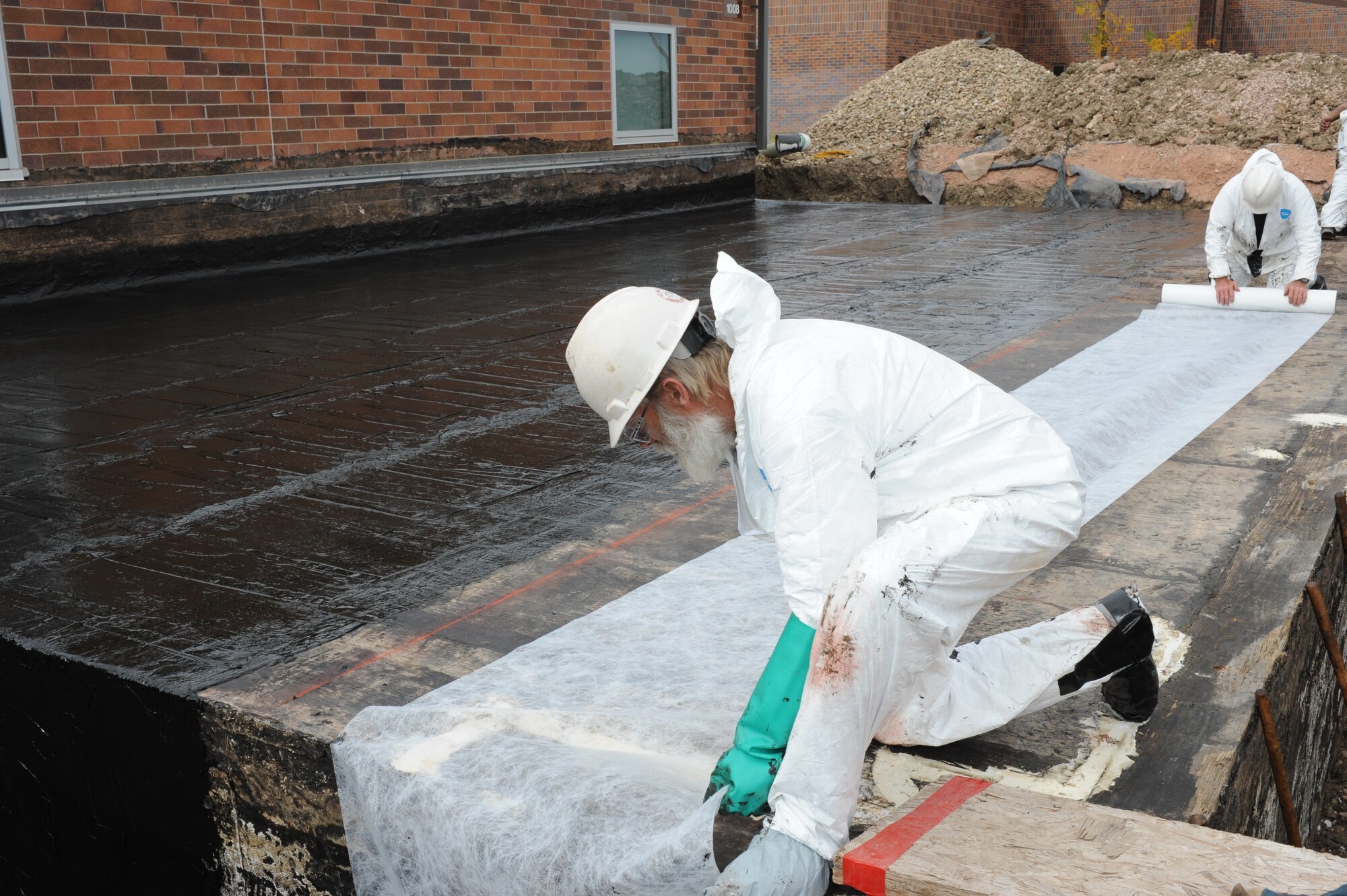 Dennis Lipp and Bruce Carpenter, Dean Kurtz construction company workers, roll out waterproofing fabric before covering the roof of a basement with sealant at Ellsworth Air Force Base, S.D., Oct. 23, 2014. The 28th Civil Engineer Squadron engineering flight worked with local contractors to repair base structures, and has contracted 47 future base projects to be designed and constructed in 2015. (U.S. Air Force photo by Senior Airman Hailey R. Staker/Released)  