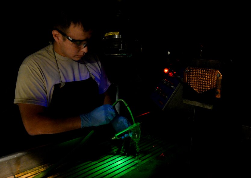 Staff Sgt. Joshua Martinez, 2nd Maintenance Squadron assistant NCO in-charge of nondestructive inspections, inspects a part using a magnetic particle machine on Barksdale Air Force Base, La., Oct. 15, 2014. The machine uses fluorescent particles that attach to cracks and defects, together with a black light defects become visible to the naked eye. (U.S. Air Force photo/Airman 1st Class Mozer O. Da Cunha)