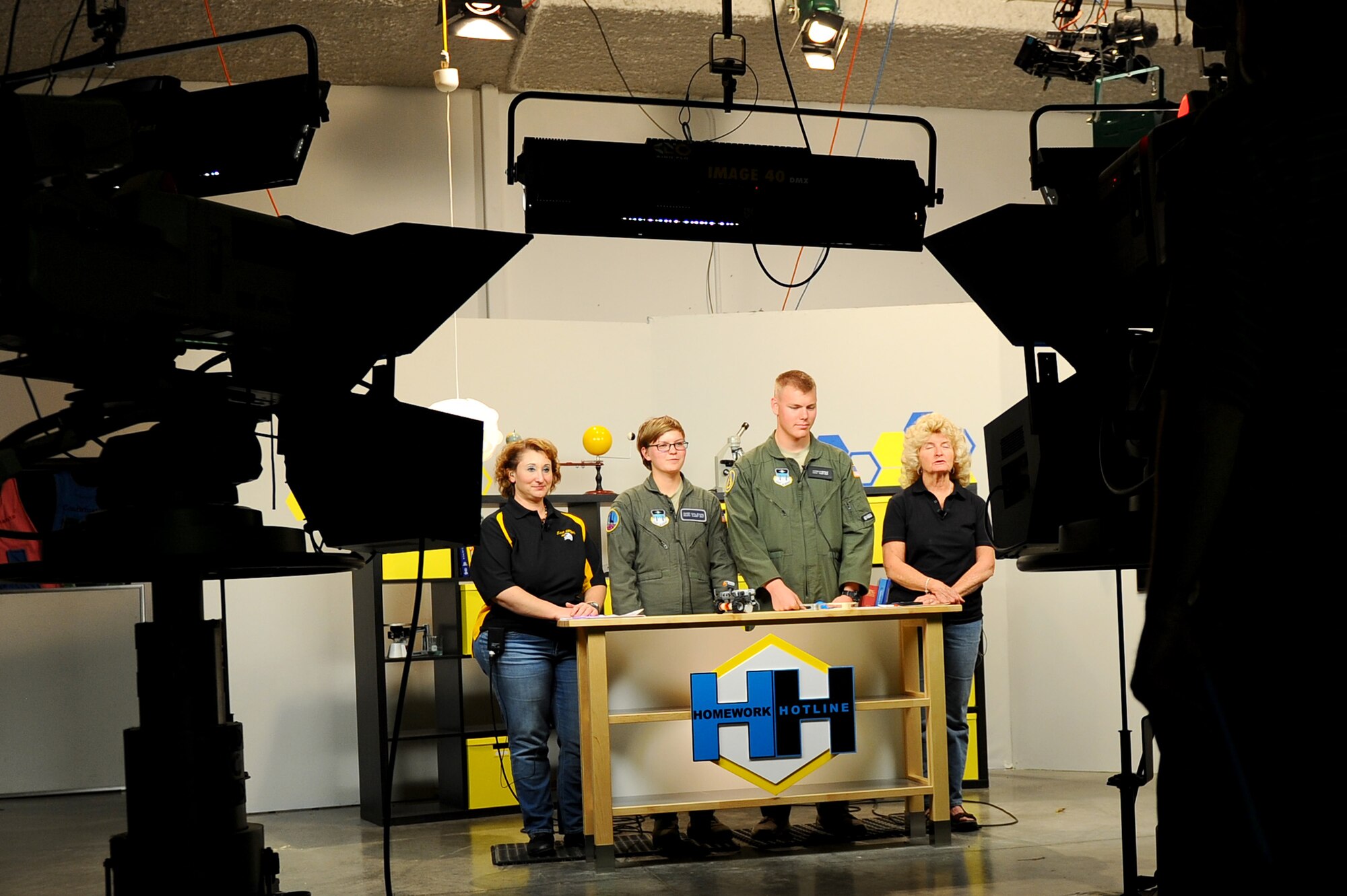 Janae Passalaqna, far left, a teacher at East High School in Pueblo, Colo., and Betty Lee, far right, a retired teacher, listen in as Cadets 3rd Class Casey Evans and Warren Metcalf explain the specifics of 3D printing at the Public Broadcasting Service at Colorado State University – Pueblo, Oct. 24, 2014. The cadets helped Passalaqna and Lee host Homework Hotline, which allows school-aged children to call in with homework-related questions. (U.S. Air Force photo/Airman 1st Class Rachel Hammes)