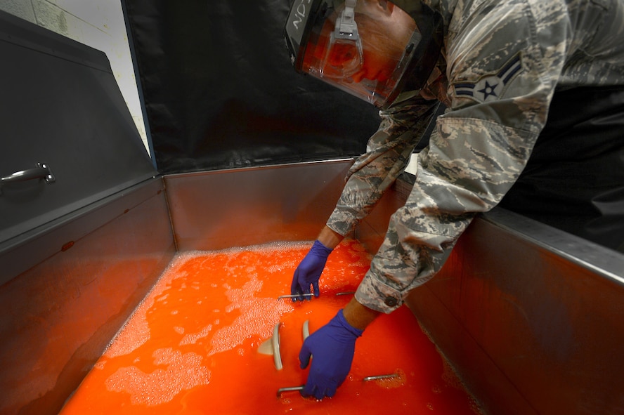 U.S. Air Force Airman 1st Class Tyler Huggins, 20th Equipment Maintenance Squadron non-destructive inspection apprentice, dips F-16CM Fighting Falcon nose landing gear wheels into a fluorescent chemical at Shaw Air Force Base, S.C. Oct. 28, 2014. During the fluorescent penetrant inspection, wheels are placed in a series of liquids that seep into any possible cracks in the metal. Once dry, they are placed under a black light to determine where cracks may be. (U.S. Air Force photo by Airman 1st Class Jensen Stidham/Released) 