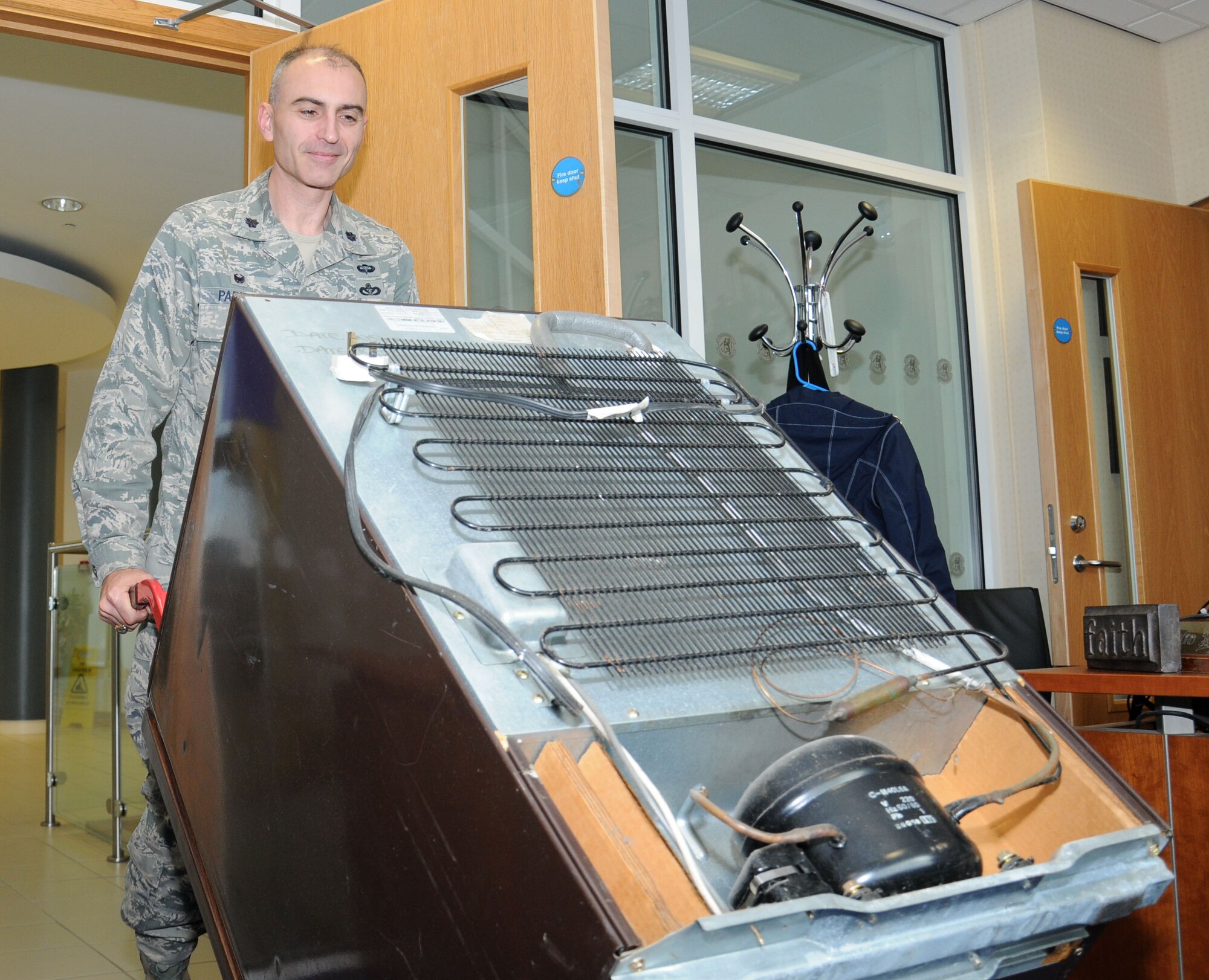 U.S. Air Force Lt. Col. Kevin Parker, 100th Civil Engineer Squadron commander, uses a hand cart to remove a personal refrigerator from his office Oct. 24, 2014, on RAF Mildenhall, England. Parker saw an opportunity to save energy by removing his refrigerator from his office and using the communal one in the kitchen area. (U.S. Air Force photo by Gina Randall/Released)