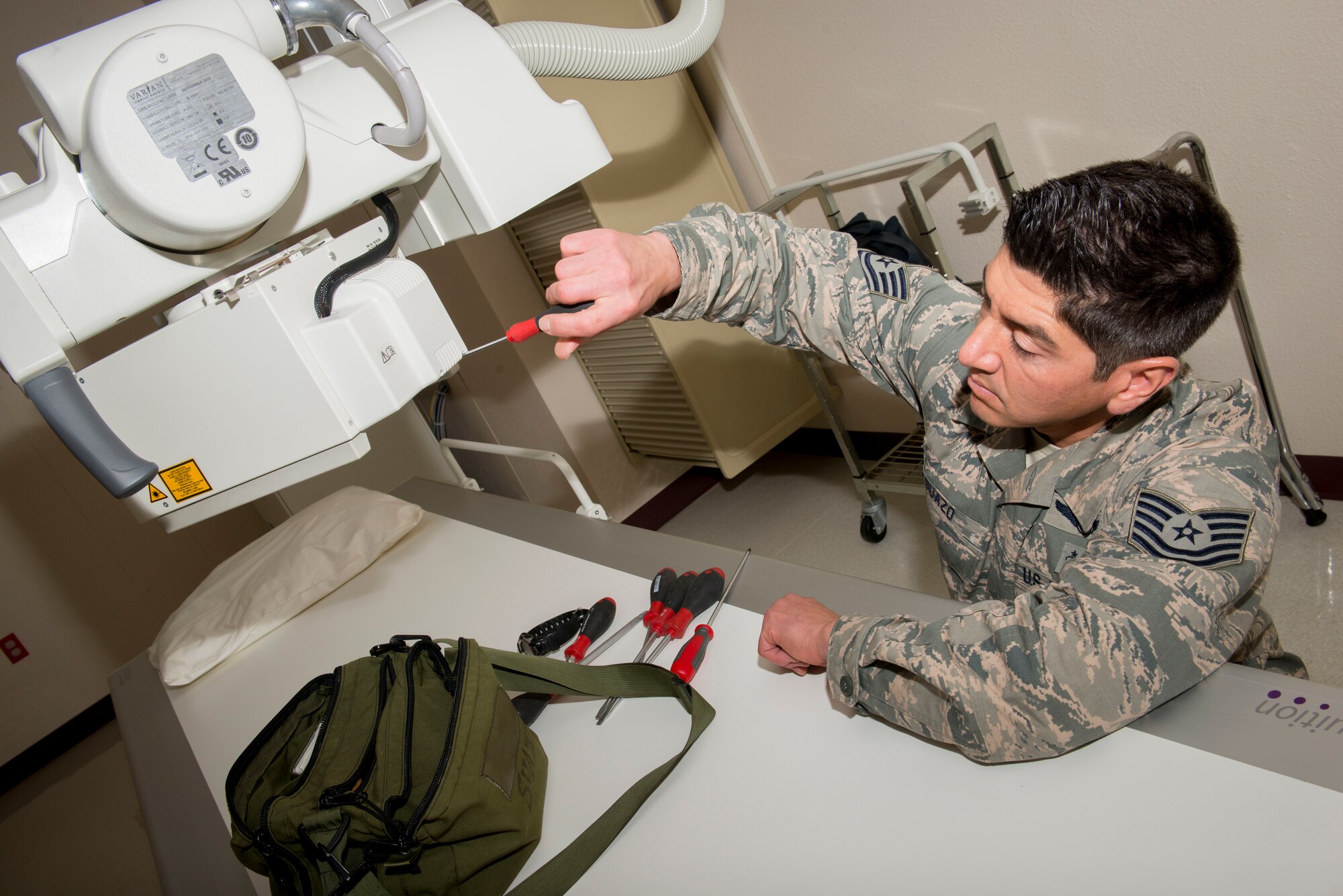 Tech. Sgt. Doug Suazo, 5th Medical Support Squadron biomedical equipment technician, removes the panels off of a radiographic x-ray unit collimator on Minot Air Force Base, N.D., Oct. 22, 2014. The collimator, made out of lead, helps protect the patient from excess scatter radiation by confining and reducing the x-ray beam. (U.S. Air Force photo/Airman 1st Class Sahara L. Fales)