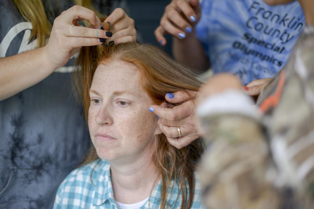 Friends braid the air of North Carolina National Guard Chaplain (Maj.) Melissa Culbreth ahead of a head shaving party in her honor.  U.S. Army photo by Staff Sgt. Mary Junell