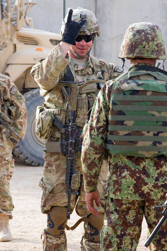 U.S. Army Staff Sgt. Brandon DeBolt, center, teaches Afghan soldiers a hand signal indicating to them to form two single-file lines during helicopter load training before a partnered air assault mission on Camp Hero, Afghanistan, Oct. 22, 2014. DeBolt is a platoon sergeant assigned to the 4th Infantry Division's Company B, 1st Battalion, 12th Infantry Regiment, 4th Infantry Brigade Combat Team.