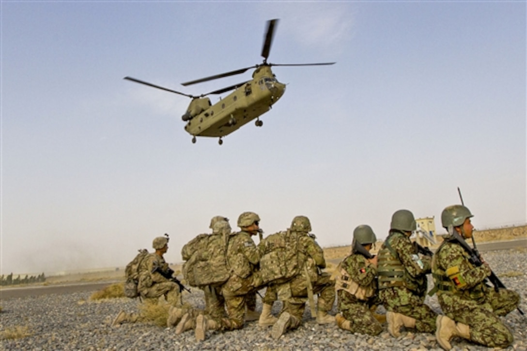 A U.S. CH-47 Chinook helicopter descends as U.S. and Afghan soldiers prepare to board to conduct a partnered air assault mission in the town of Mirugal Kalay near Camp Hero, Afghanistan, Oct. 23, 2014. The mission was the first time the 4th Infantry Division's Company B, 1st Battalion, 12th Infantry Regiment, 4th Infantry Brigade Combat Team was able to partner with Afghan soldiers on an air assault. 