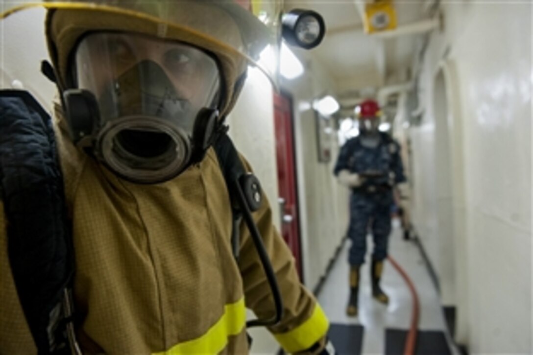 Navy Petty Officer 2nd Class Zachary Turner tends a fire hose during a general quarters drill aboard the aircraft carrier USS John C. Stennis in Bremerton, Wash., Oct. 27, 2014. The Stennis is undergoing a docking planned incremental availability maintenance period at Puget Sound Naval Shipyard and Intermediate Maintenance Facility.
