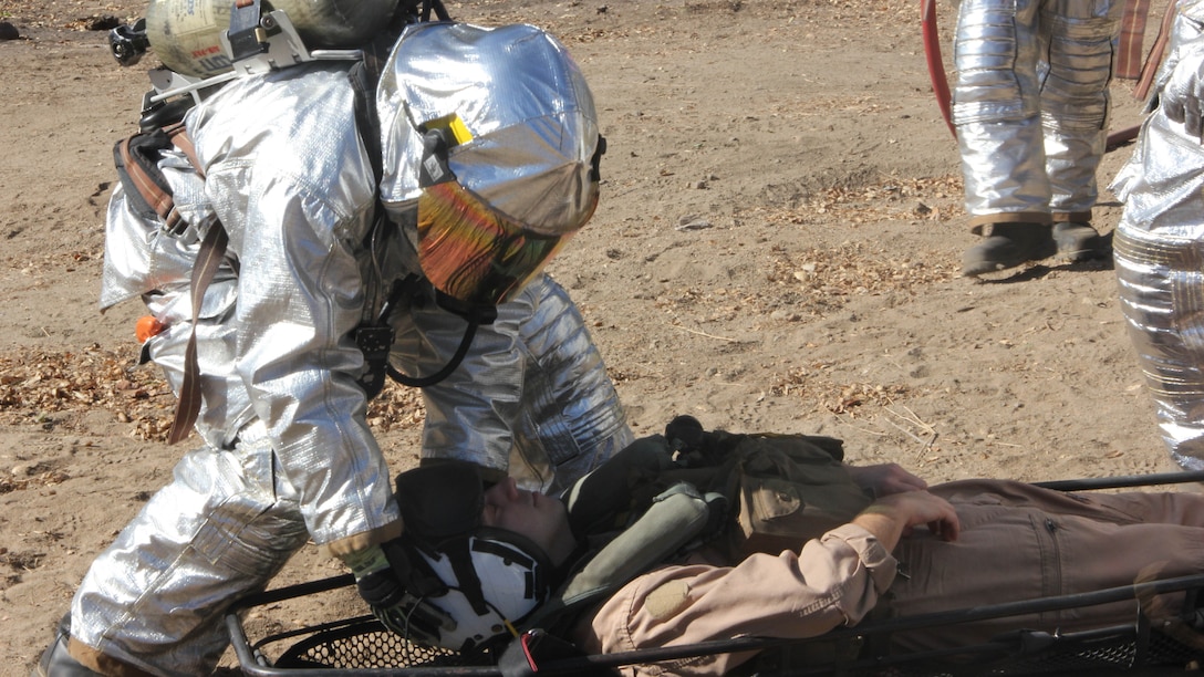 A Marine with Aircraft Rescue and Firefighting, Headquarters and Headquarters Squadron, 3rd Marine Air Wing, I Marine Expeditionary Force, stabilizes a simulated casualty during a mishap drill at Marine Corps Base Camp Pendleton, Calif., Oct. 27, 2014. The drill provided first responders the opportunity to practice every step of responding to a disabled aircraft including coordinating military and civilian agencies and rescuing the crew of the aircraft. 