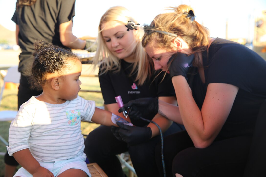 Olivia Jen-Charles, two, looks on as employees from Jolly Jumps Express Events give her a temporary tattoo at Del Valle Field during the Family Fall Festival, Oct. 24, 2014. The festival included mostly free events and activities. For the events that weren’t free, families could purchase tickets at designated Marine Corps Community Services tables.