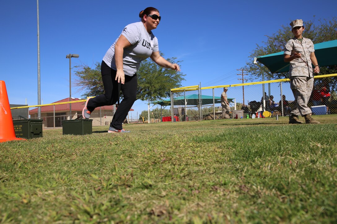 Lance Cpl. Cinthya Garcia, administrative specialist, Headquarters Battalion, times Brieann Anderson, spouse, as she begins the movement under fire portion of her Combat Fitness Test during the Combined Arms Exercise for Spouses at Felix Field, Oct. 23, 2014. CAX for Spouses provides loved ones with a day-in-the-life experience of a Marine.