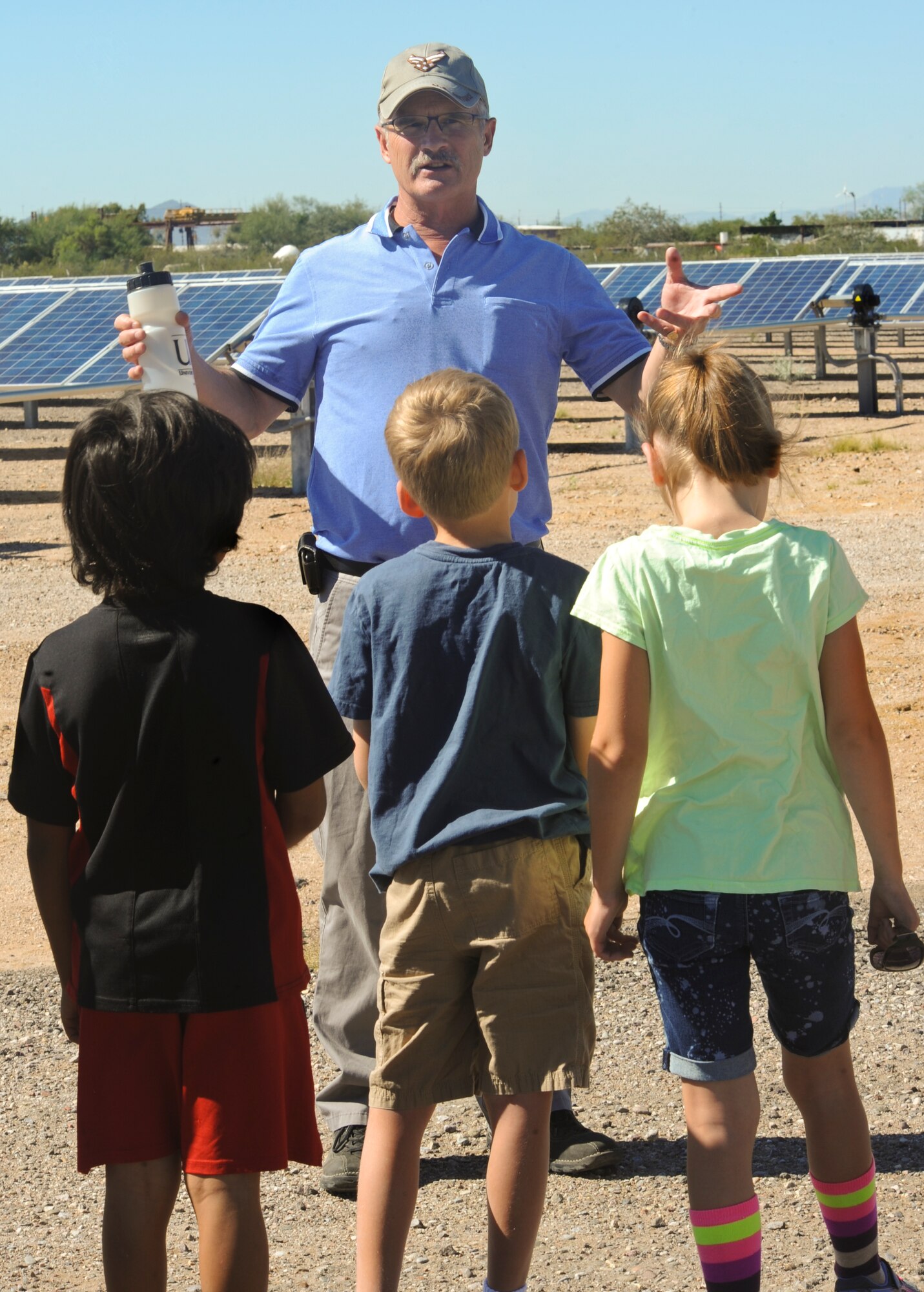 Greg Nobel, 355th Fighter Wing energy manager, explains what solar panels do to children from Borman Elementary School around the 16.4 megawatt Solar Array to celebrate Energy Action Month at Davis-Monthan Air Force Base, Ariz., Oct. 22, 2014. The 355th Civil Engineering Squadron partnered with local schools to help educate the students on benefits of conserving energy. (U.S. Air Force photo by: Staff Sgt. Angela Ruiz/Released) 